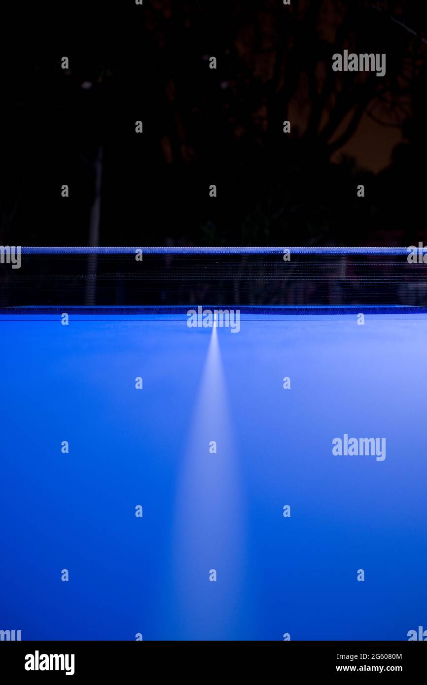 photographie à angle bas prise la nuit de la ligne centrale et du filet sur table bleue de tennis de table Banque D'Images