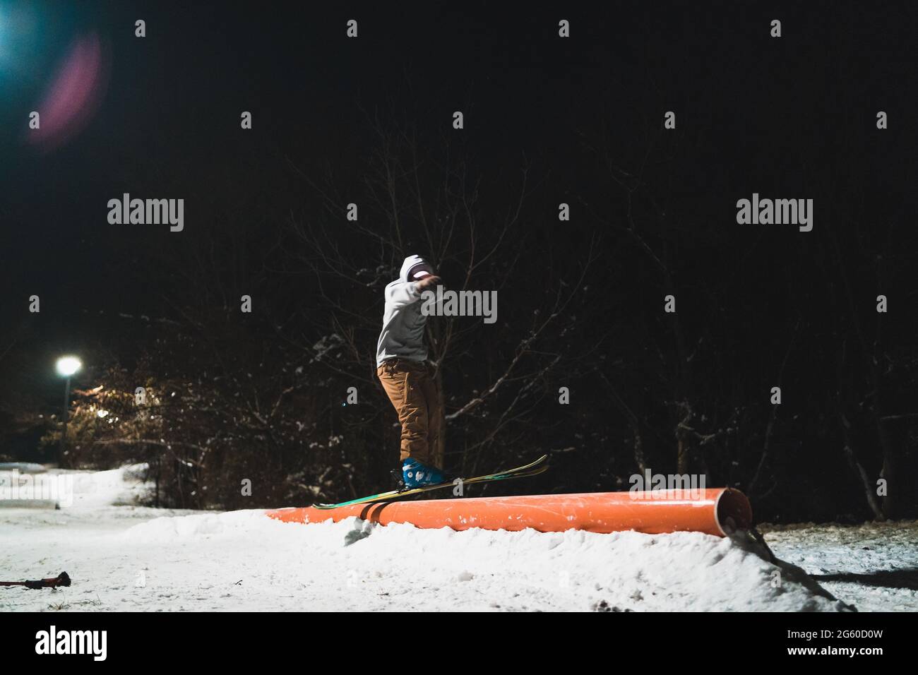 Un skieur freestyle meulant un rail sur ses skis la nuit Banque D'Images