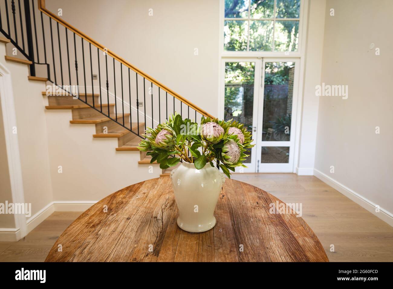 Vue générale de l'intérieur de la maison avec table et vase avec fleurs dans le grand couloir et escalier Banque D'Images