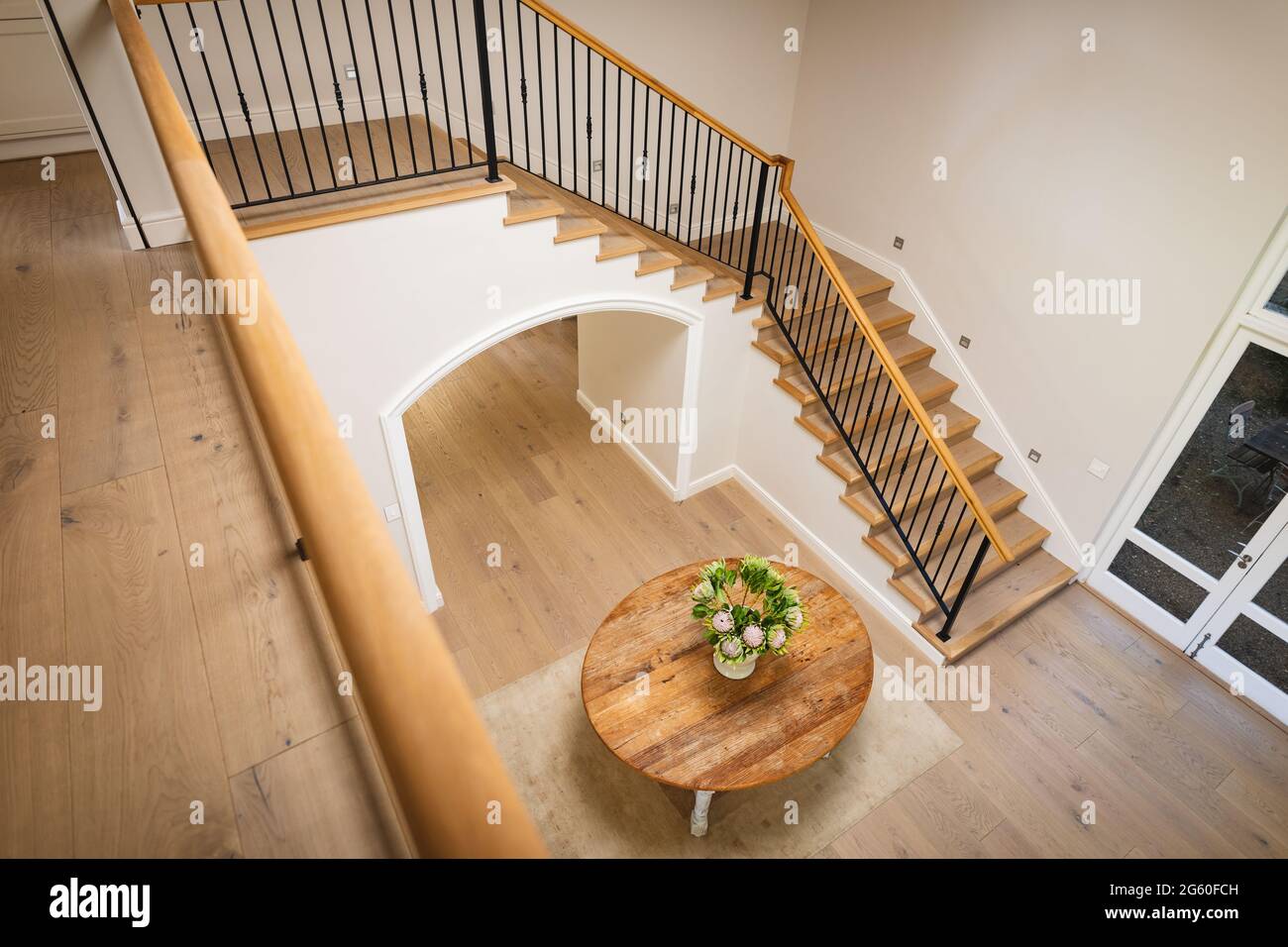 Vue générale de l'intérieur de la maison avec table et vase avec fleurs dans le grand couloir et escalier Banque D'Images