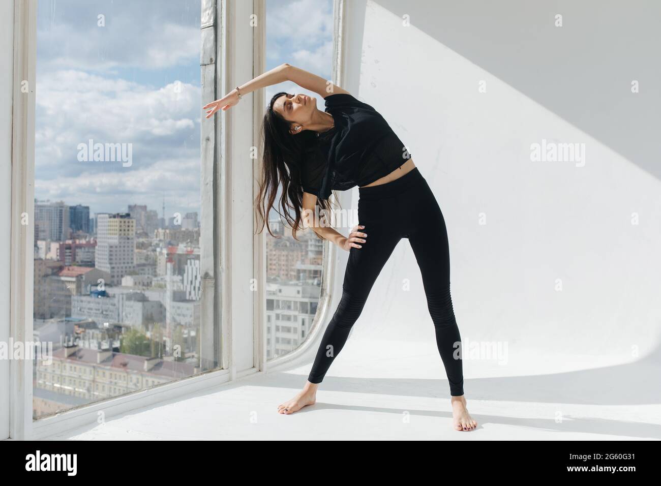 vue en longueur de la femme arménienne en fente latérale avec la main sur la hanche près de la fenêtre Banque D'Images