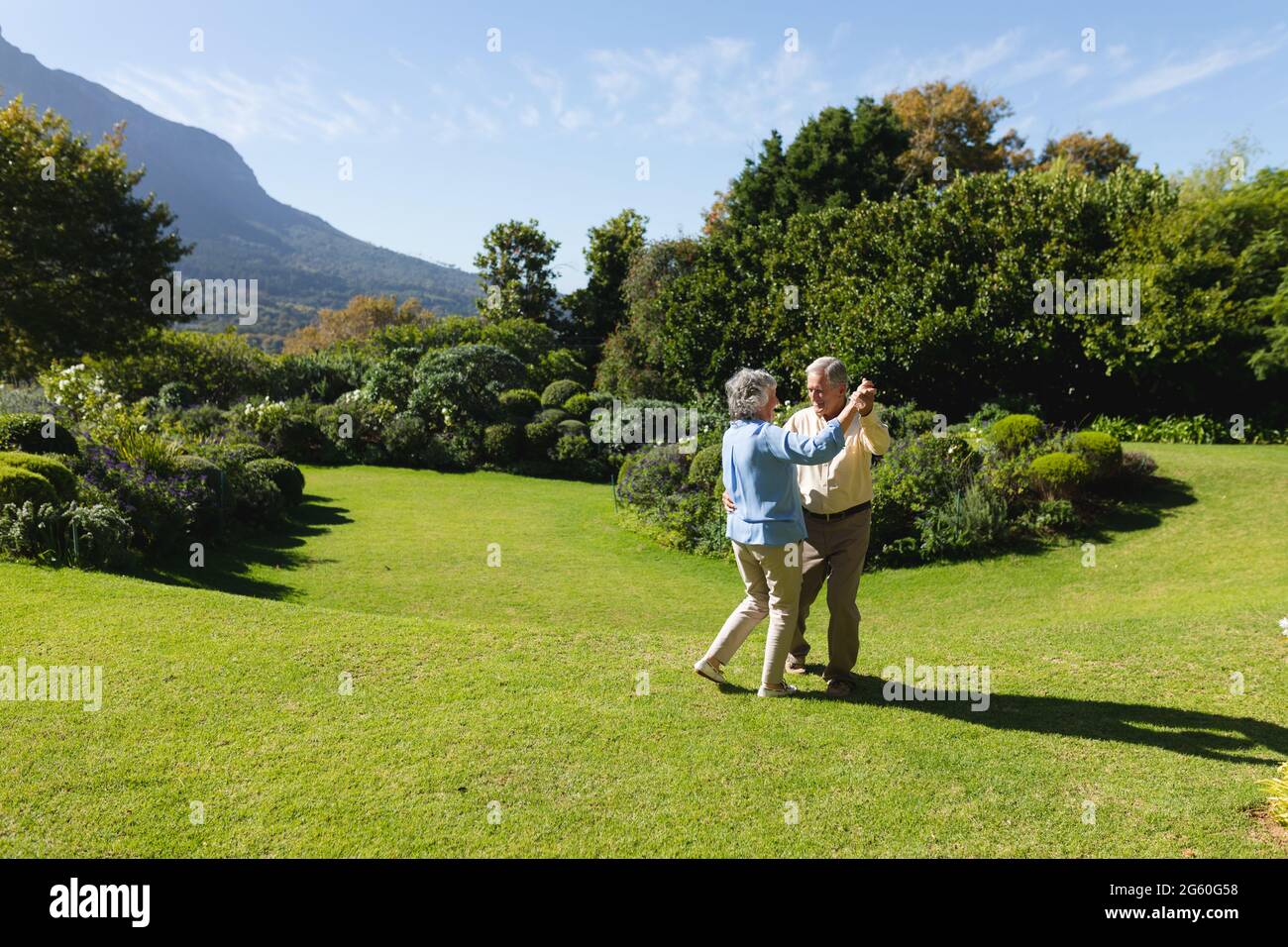 Couple caucasien senior dansant ensemble dans un jardin ensoleillé Banque D'Images