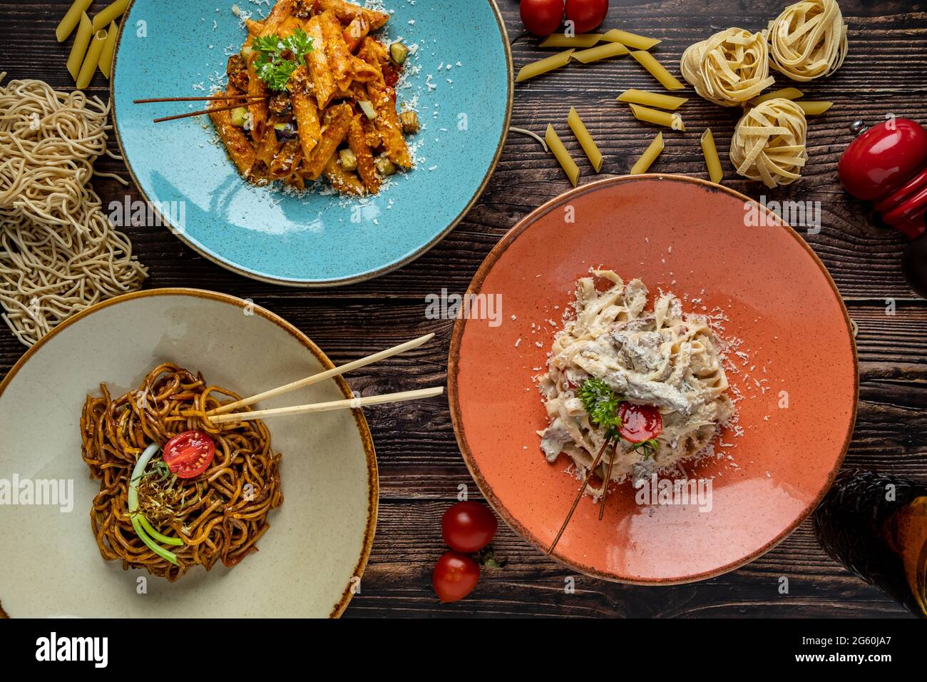 Pâtes de nouilles, de fettuccine et de penne sur trois assiettes séparées sur fond de bois. Banque D'Images