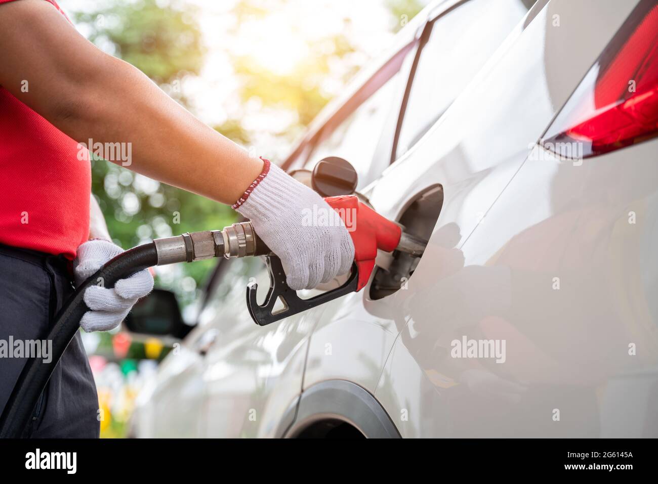 Le préposé au ravitaillement en gaz qui porte des gants fait le plein des  clients, pompant le gaz de l'équipement à la station-service Photo Stock -  Alamy