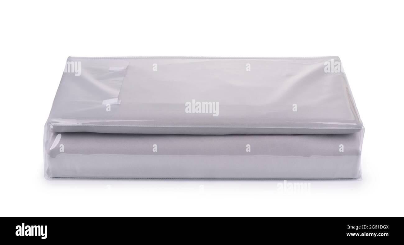Draps de lit en coton gris pliés dans un sac en plastique transparent isolé sur du blanc Banque D'Images