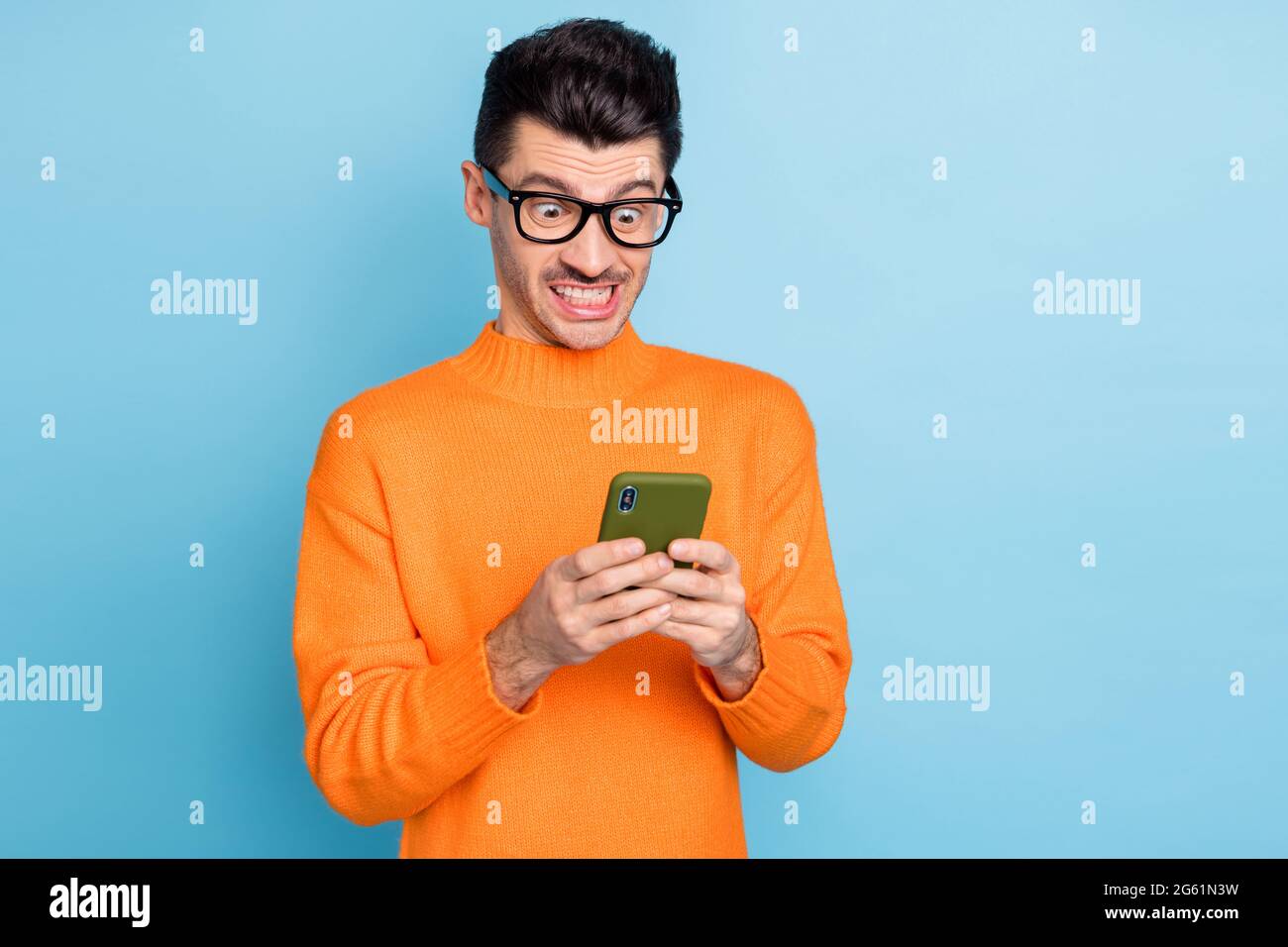 Photo d'un jeune homme malheureux fou look smartphone n'aime pas chat type sms isolé sur fond bleu de couleur Banque D'Images