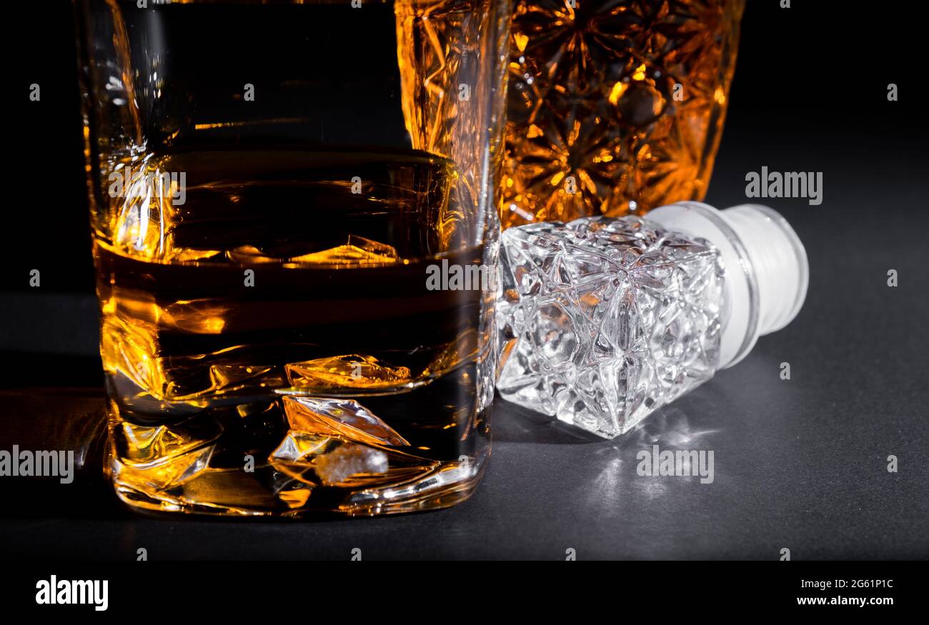 Gros plan d'un verre de cristal avec une bouteille de whisky sur fond noir.  Queues de cokéfaction et spiritueux Photo Stock - Alamy