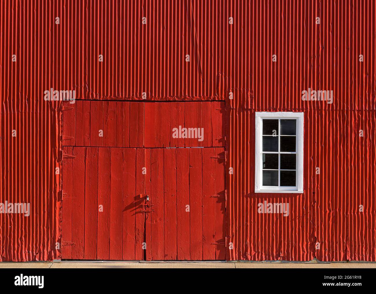 Portes rouges en bois fermées contre le mur extérieur de la grange en bois rouge vif Banque D'Images