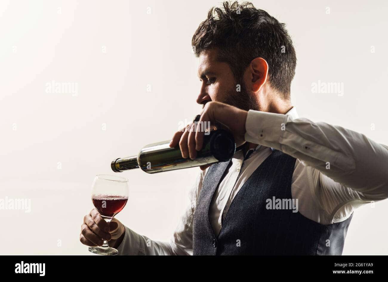 Homme barbu avec une bouteille et un verre de vin. Dégustation de vin par un sommelier au restaurant. Dégustation d'alcool. Banque D'Images