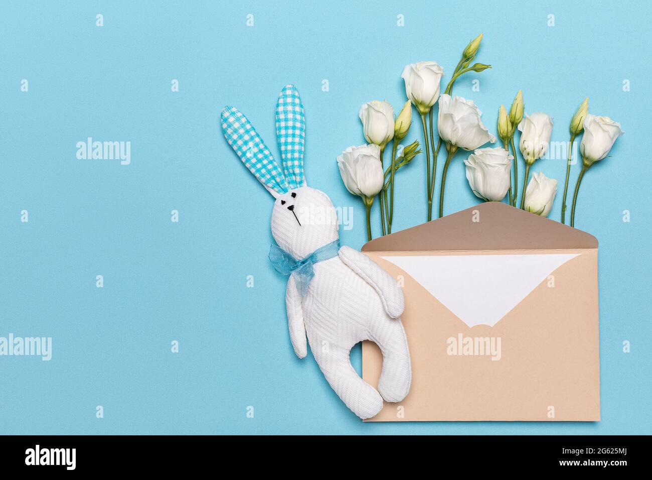 Blanc jouet lapin lièvre fait à la main et enveloppe en papier avec fleurs plates sur fond bleu. Concept de printemps et romance de lettres et de cartes pour Hol Banque D'Images