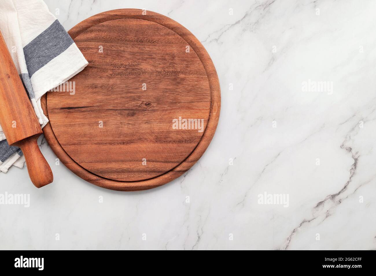 Assiette à pizza en bois vide avec serviette et rouleau sur table de cuisine en pierre de marbre. Banque D'Images