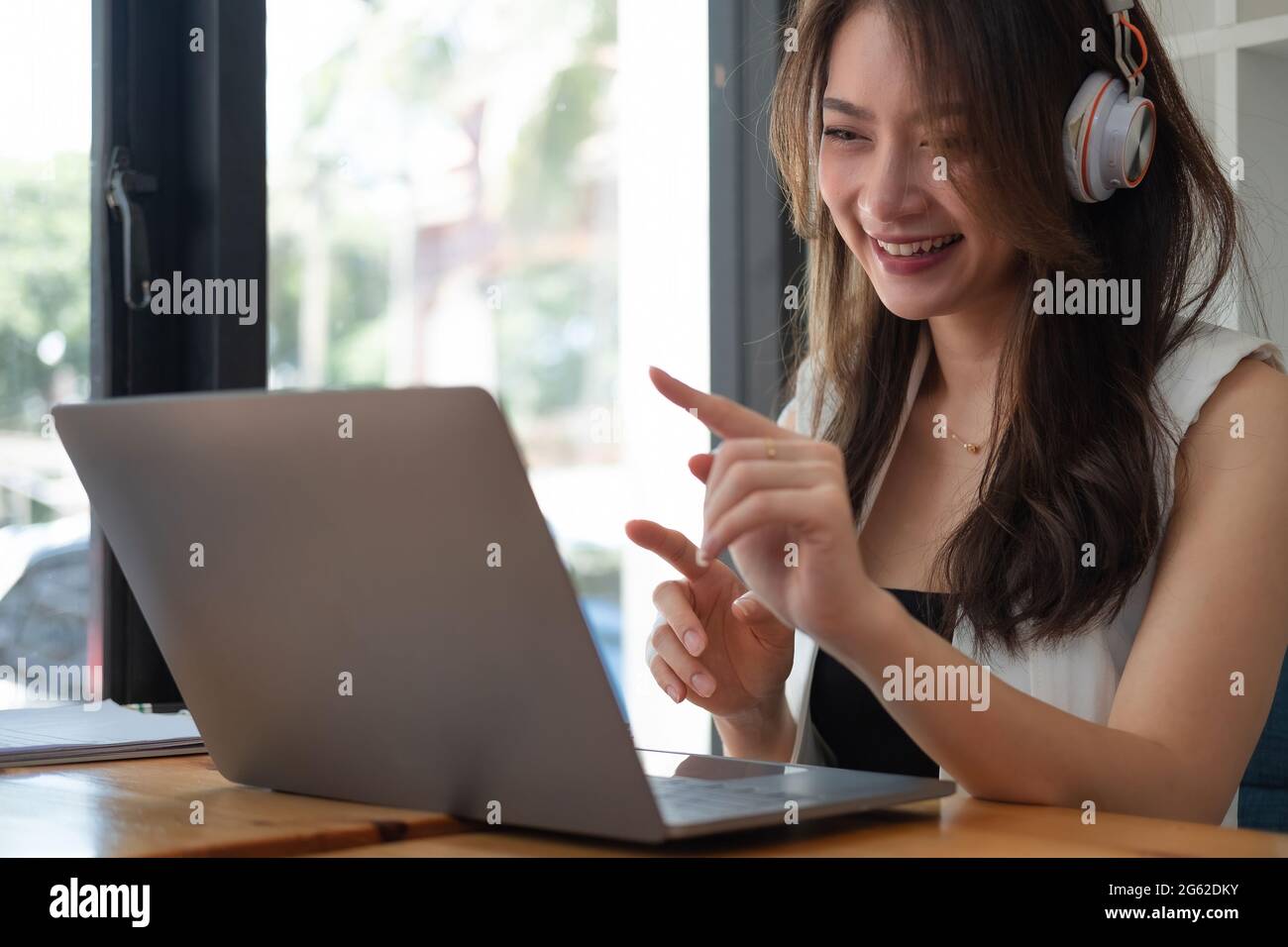Prise de vue d'une femme d'affaires asiatique heureuse portant un micro-casque/oreillette en ligne vidéoconférence sur ordinateur portable avec son équipe d'affaires pendant la quarantaine Covid-19 Banque D'Images