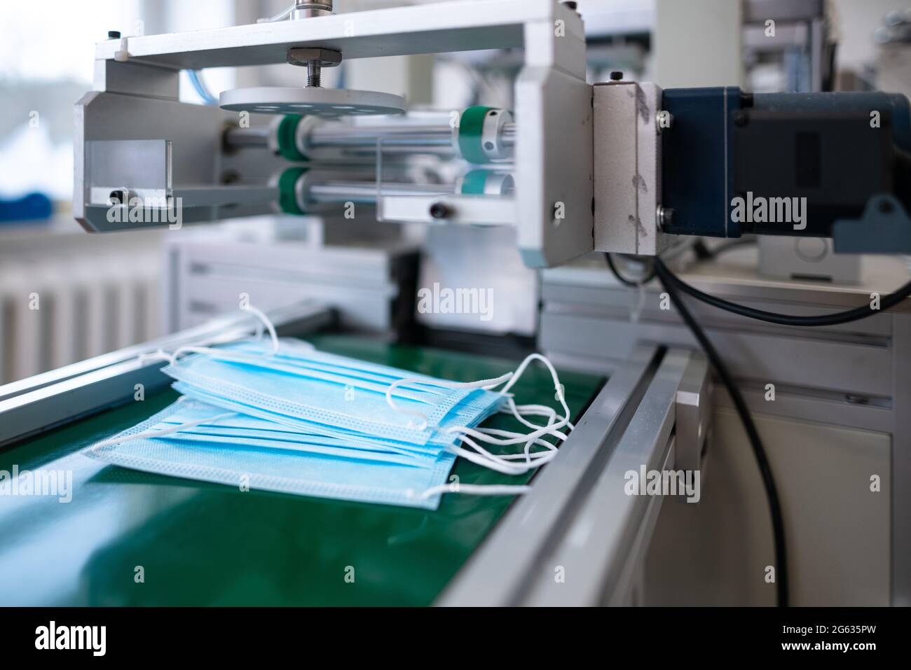 Gros plan procédé de fabrication de masques médicaux dans une usine. Machines automatisées qui font des masques médicaux respiratoires en grandes quantités. Banque D'Images