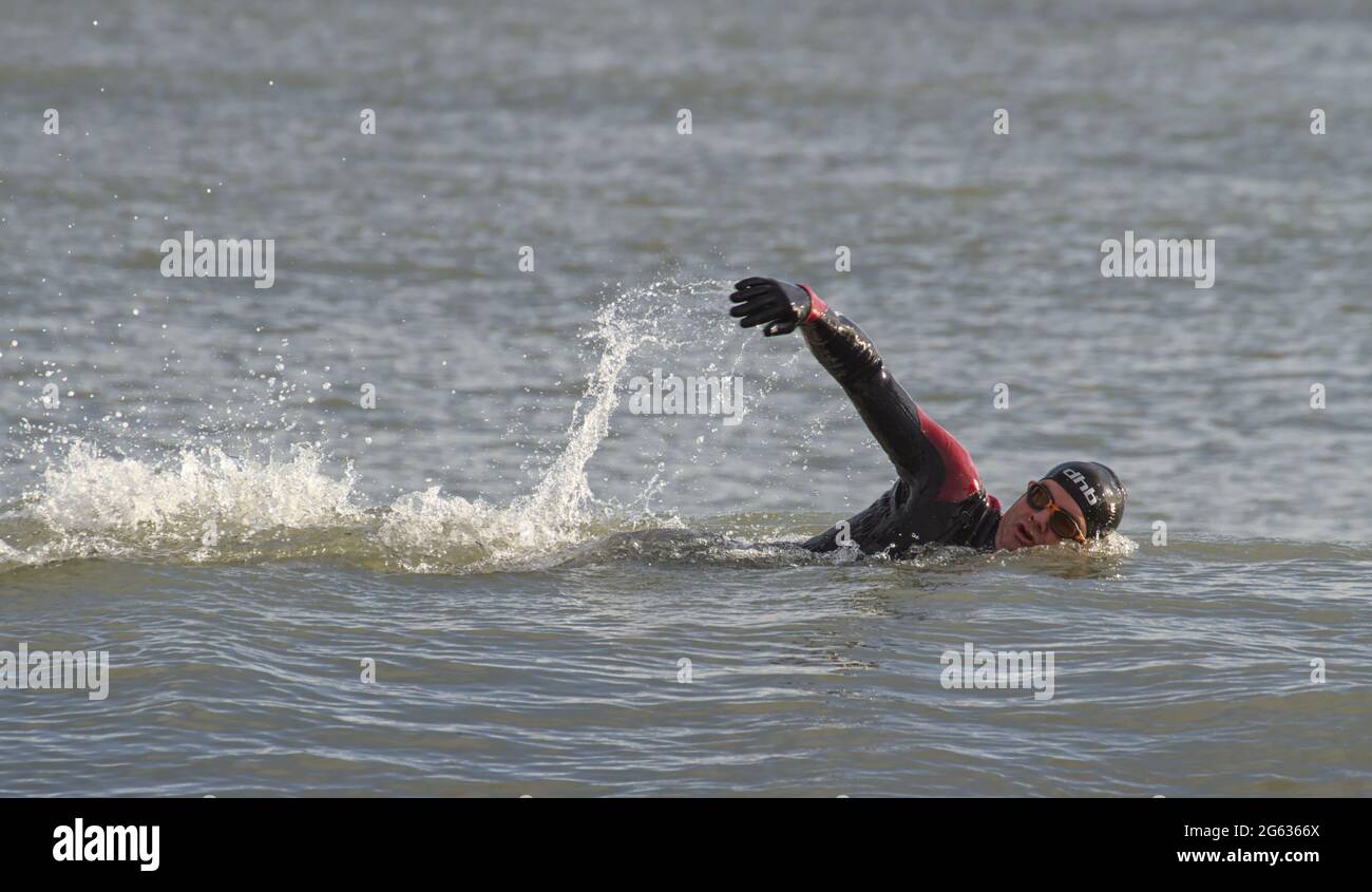 Man Wild Swimming en utilisant la couverture avant dans la mer portant UN costume humide, chapeau et Googles, Avon Beach UK Banque D'Images