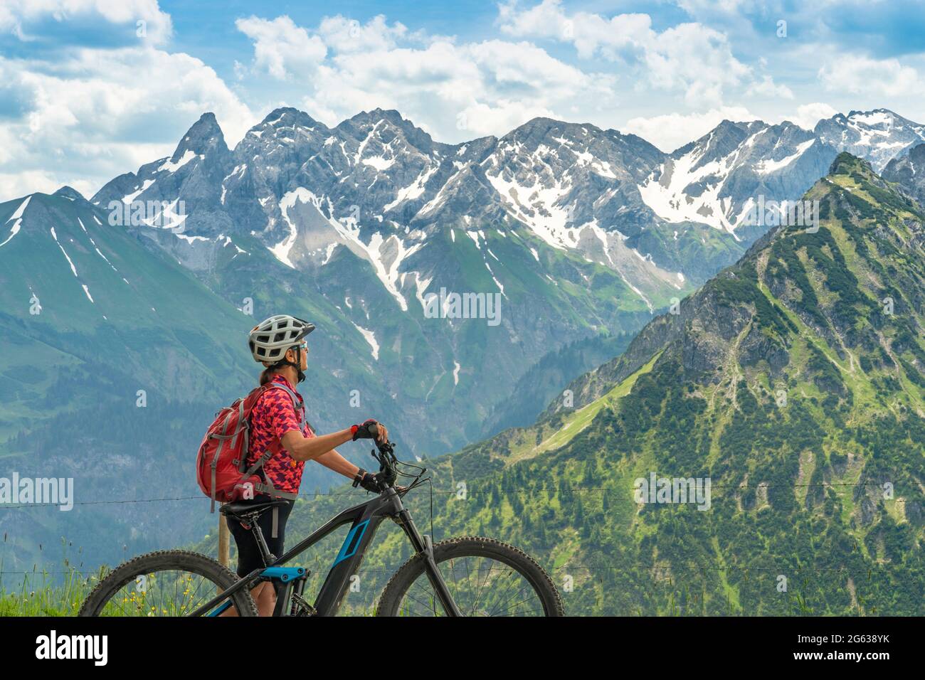 Belle femme senior en VTT grimpant sur le Mont Fellhorn en admirant les hautes Alpes d'Allgaeu avec Trettach et Maedelegabel en arrière-plan, Bavière, Banque D'Images