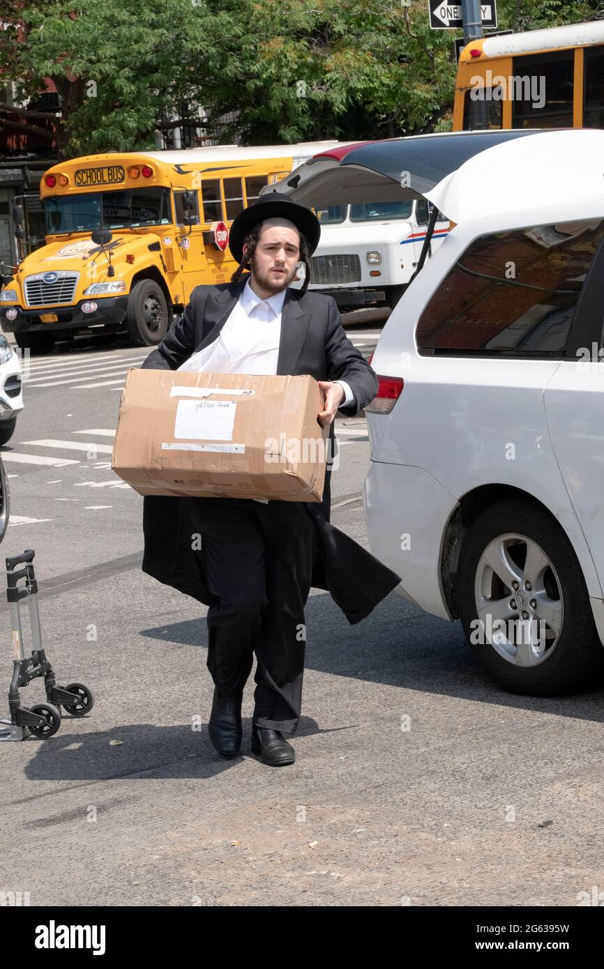 Les hommes juifs orthodoxes prennent des paquets des articles d'été de leur frère pour être utilisés dans le camp auquel ils vont assister. À Williamsburg, Brooklyn, New York. Banque D'Images