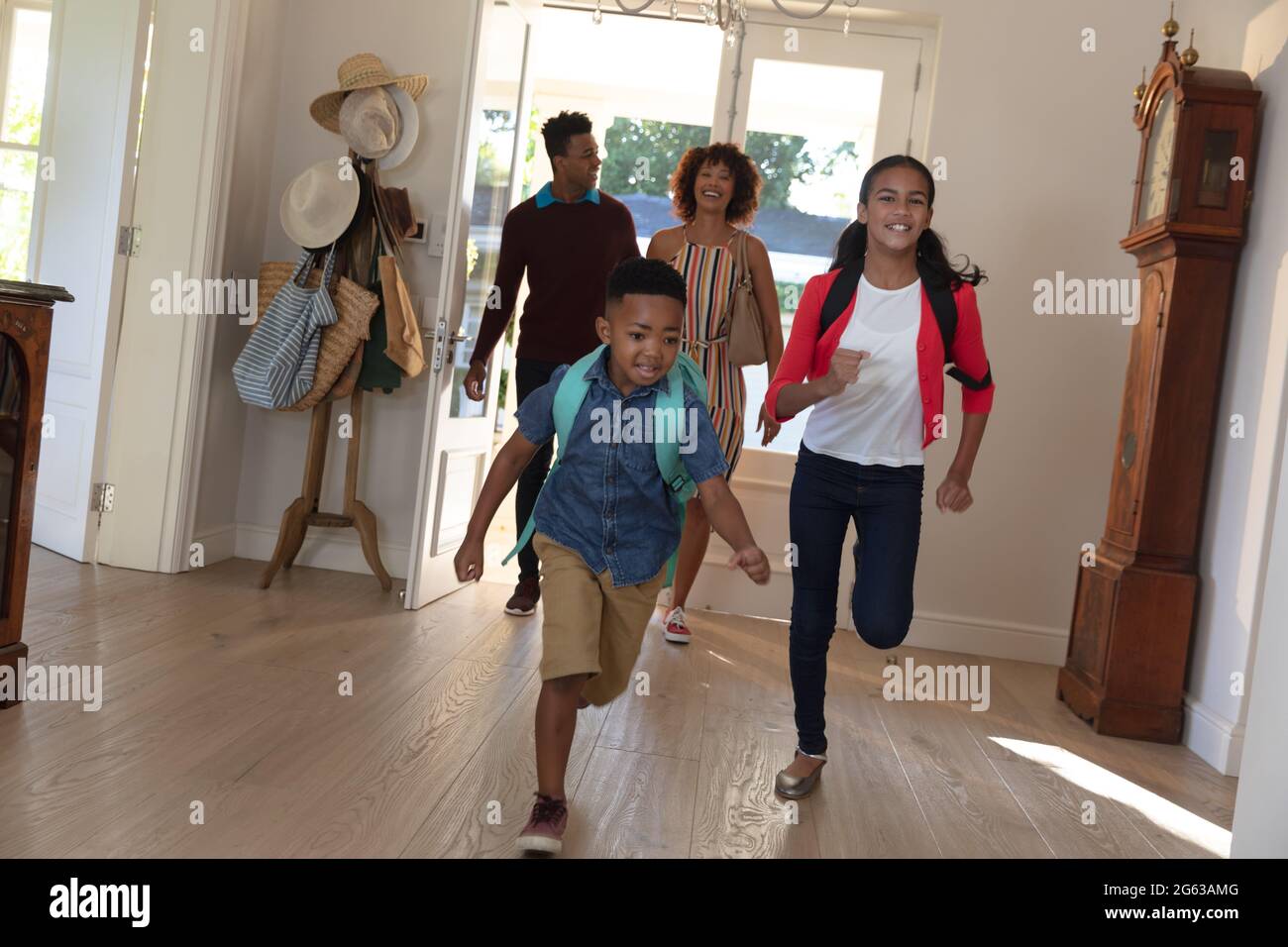Heureux couple afro-américain avec son fils et sa fille de retour de l'école embrassant et souriant à la maison Banque D'Images