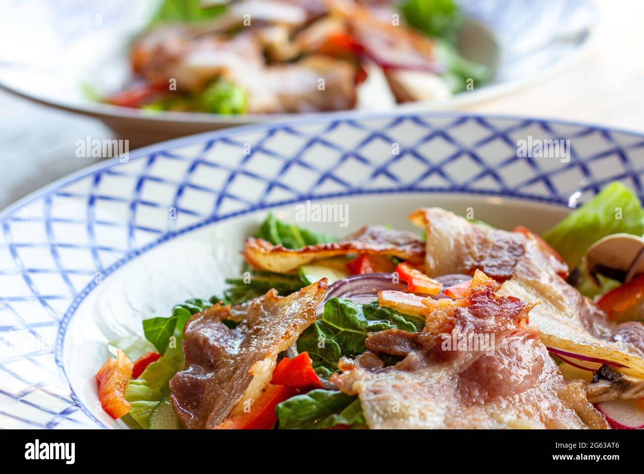 Salade verte fraîche, légumes et bacon frits dans le bol pour le déjeuner sur fond de table en bois. Banque D'Images