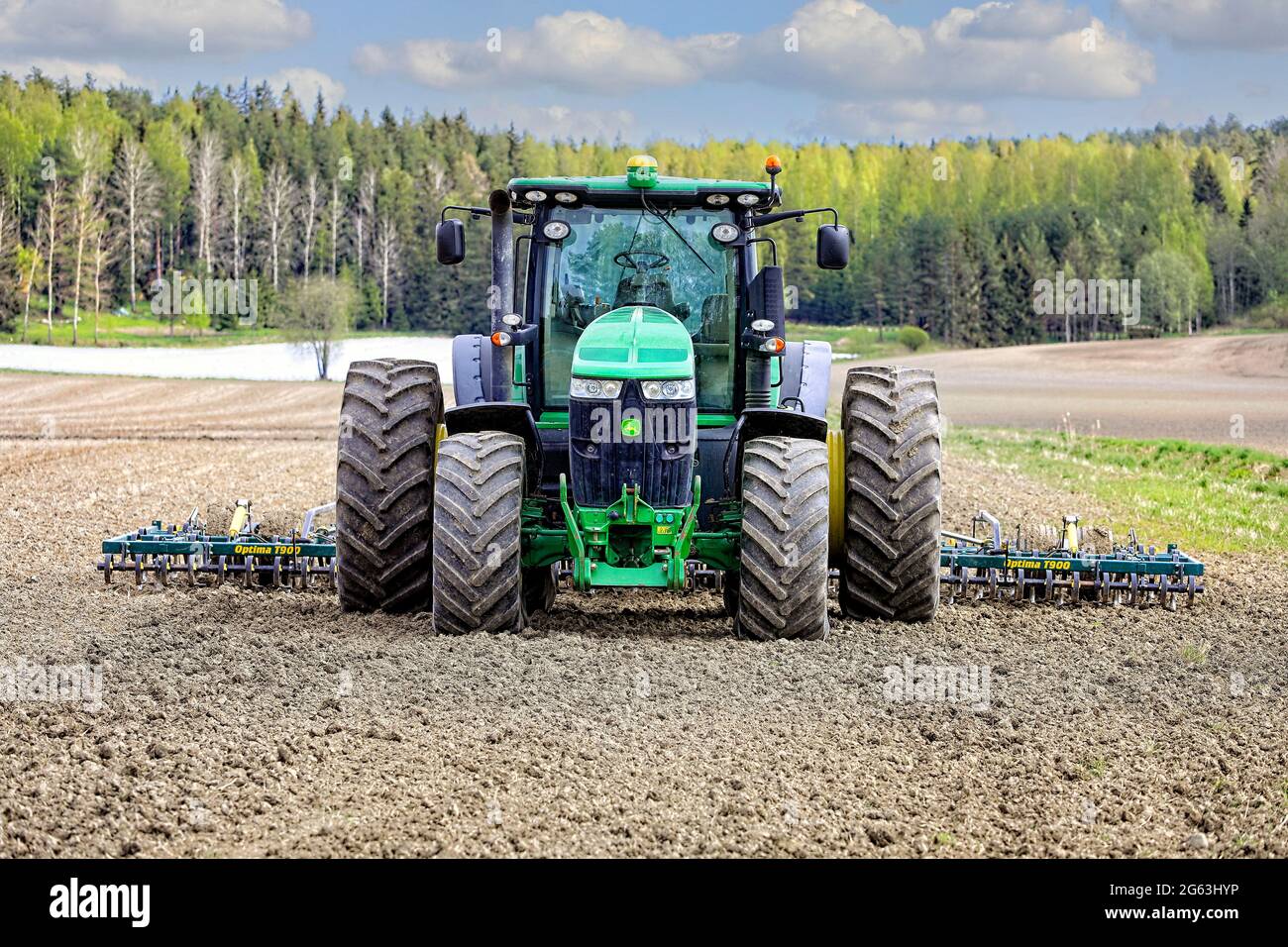 Tracteur John Deere 7230R et herse Multiva Optima T900 en champ, un jour de ressort, vue avant. Salo, Finlande. 16 mai 2021. Banque D'Images