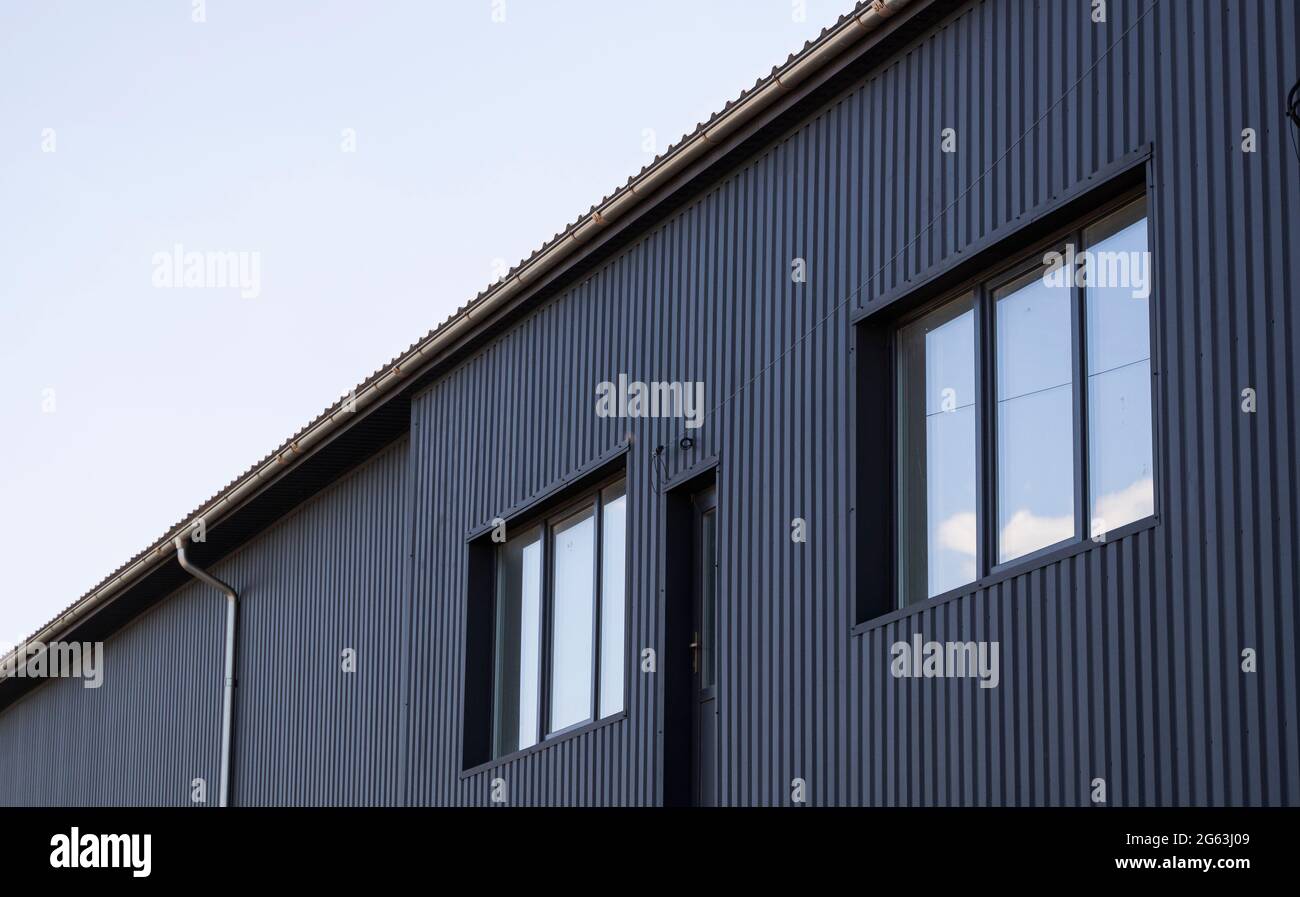 Tôle de fer ondulée noire utilisée comme façade d'un entrepôt ou d'une  usine avec des fenêtres. Texture d'une tôle d'aluminium en zinc ondulé sans  soudure Photo Stock - Alamy