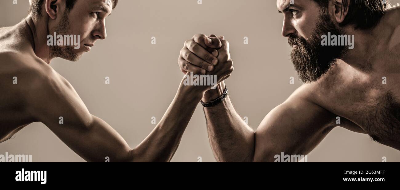 Deux mains d'homme ont un bras de lutte, forte et faible, match inégal. Homme barbu fortement musclé bras luttant un homme faible et puny Banque D'Images