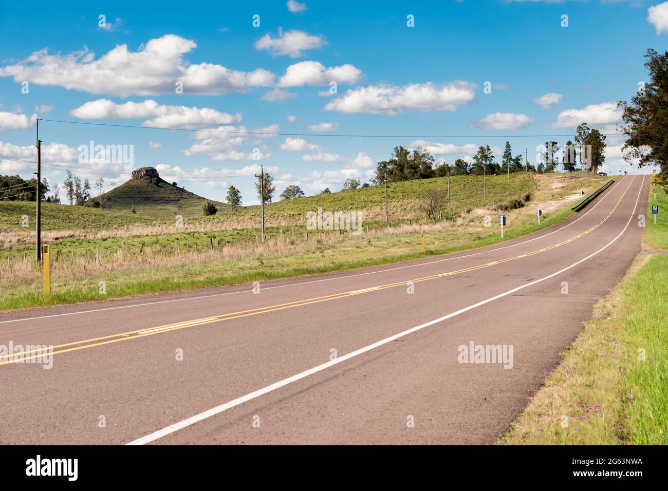 Une route sans voitures et quelques collines en arrière-plan en Uruguay, à côté de Tacuarembó. Une vue classique de la colline de Batovi est visible à l'horizon. Banque D'Images