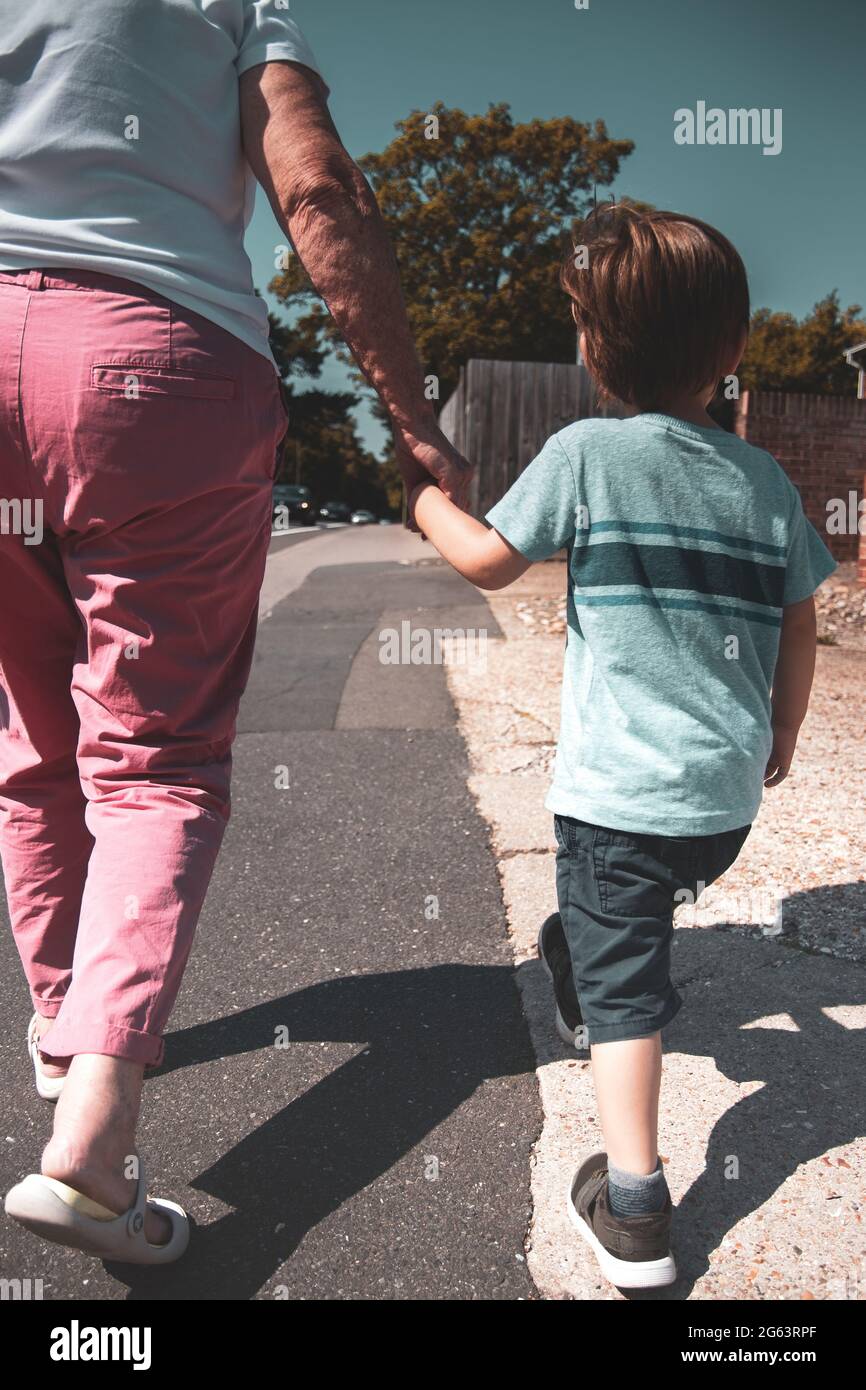 un enfant tenant les mains et étant dirigé par un parent ou un grand-parent Banque D'Images