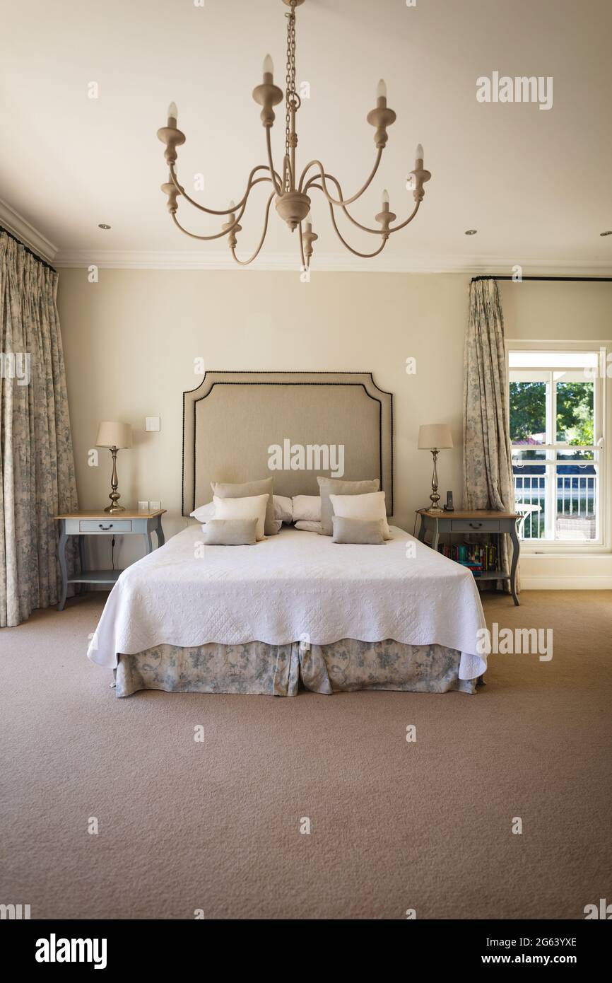 Vue générale de la chambre ensoleillée de luxe avec grand lit et tables de nuit Banque D'Images