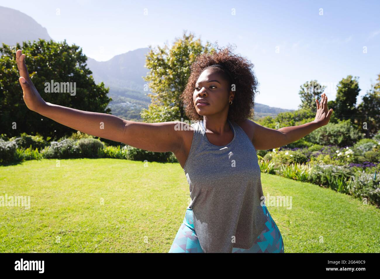 Femme afro-américaine pratiquant le yoga dans un jardin ensoleillé Banque D'Images