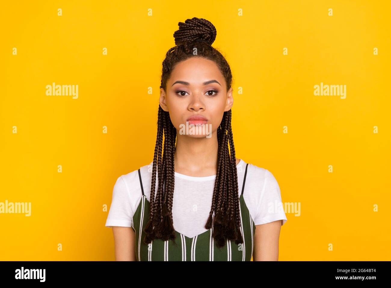 Photo de la jeune femme grave peau sombre calme paisible visage dreadlocks cheveux isolés sur fond jaune Banque D'Images