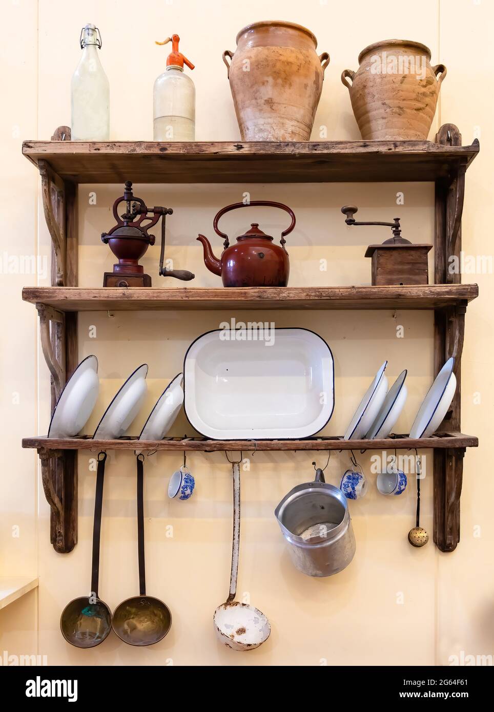 Vieux ustensiles de cuisine sur des étagères en bois et fixés au mur Banque D'Images