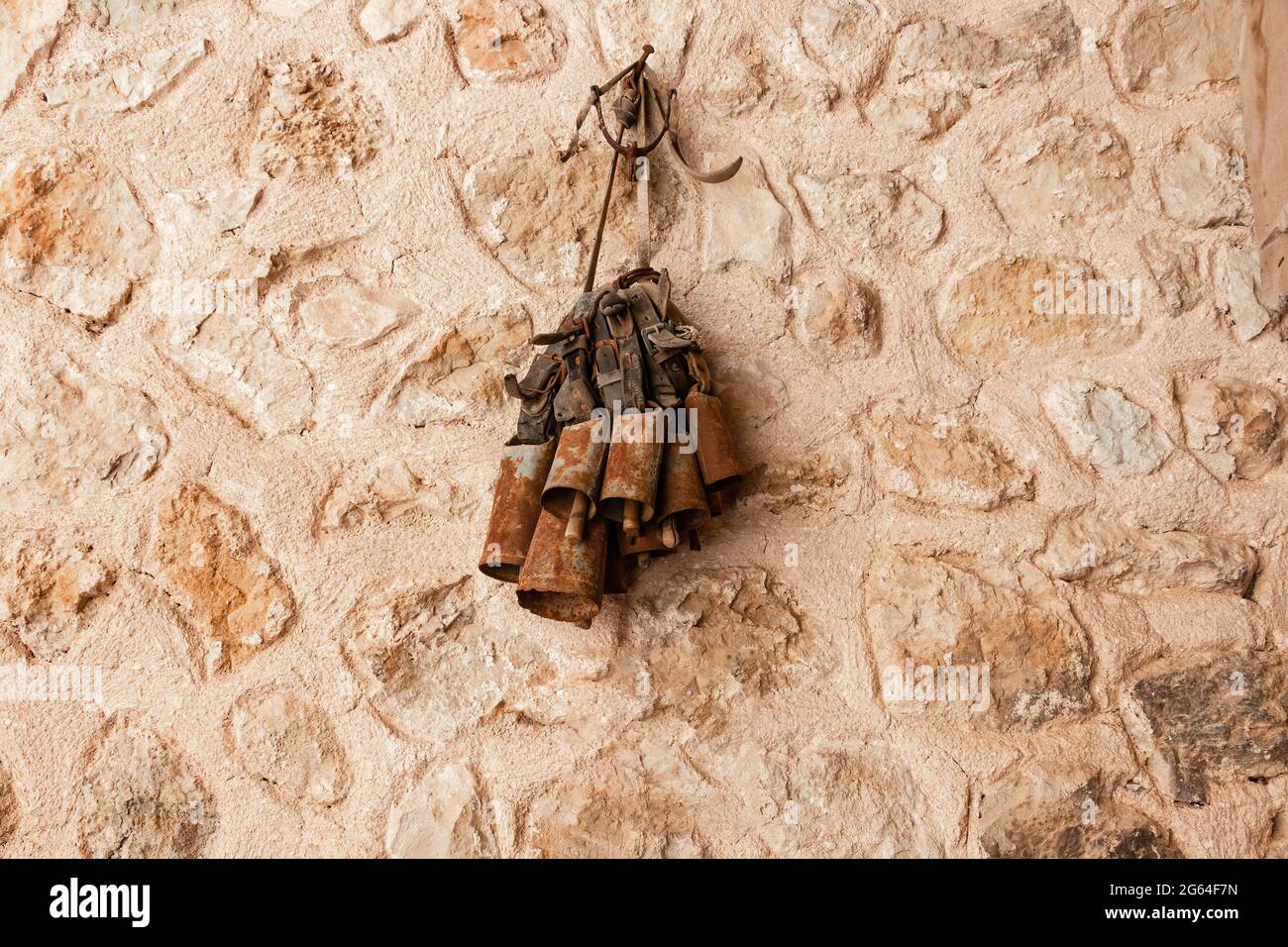 Cloches rouillées pour le bétail accrochées sur un mur en pierre Banque D'Images