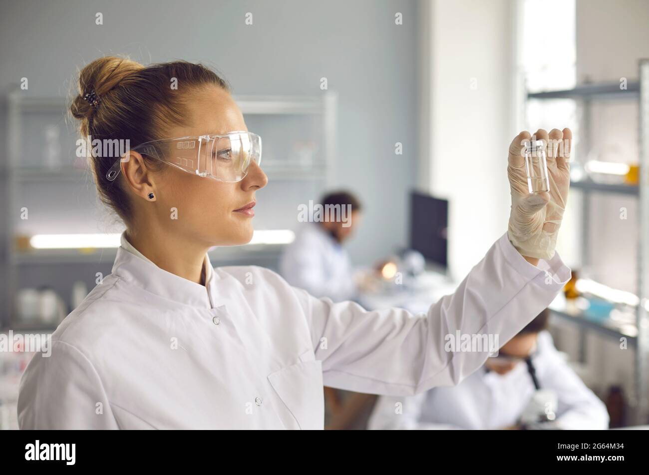 Une jeune scientifique regarde un tube à essai avec une substance blanche. Banque D'Images