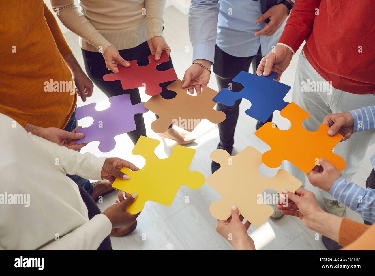 Une équipe de personnes s'associe à des pièces de puzzle colorées pour trouver une solution et un travail d'équipe Banque D'Images