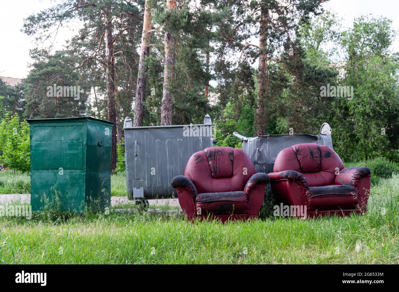 Deux chaises en cuir rouge. Meubles dans la poubelle. Lieu de travail dans la forêt. Mobilier de décharge sanitaire. Mobilier en bois. Banque D'Images