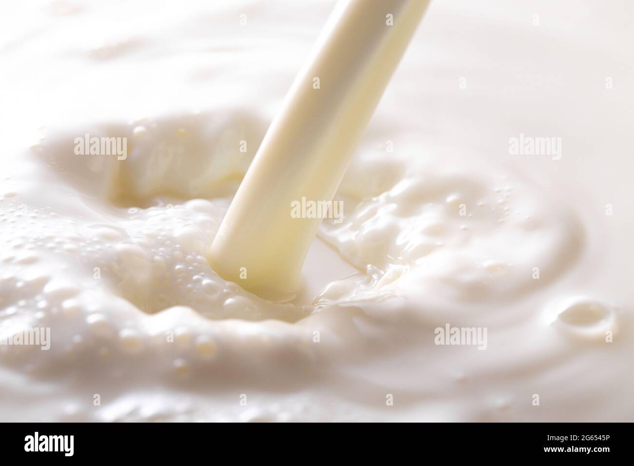 Une vapeur de lait versée dans un bol de lait Banque D'Images