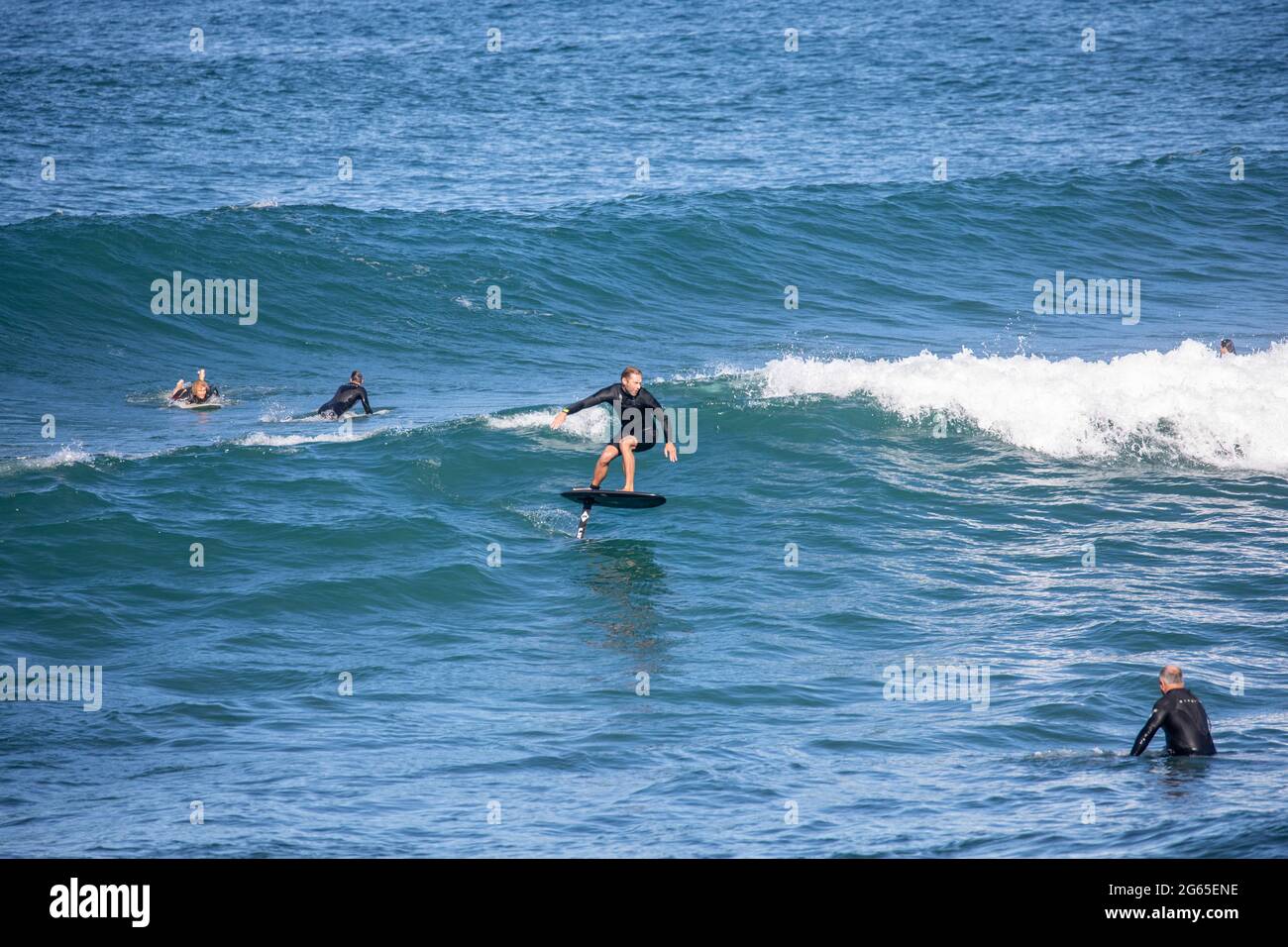Surfeur d'hydroglisseur et surfeurs de surf dans l'océan au large de la plage de Sydney, en Nouvelle-Galles du Sud, en Australie, par une journée hivernale Banque D'Images