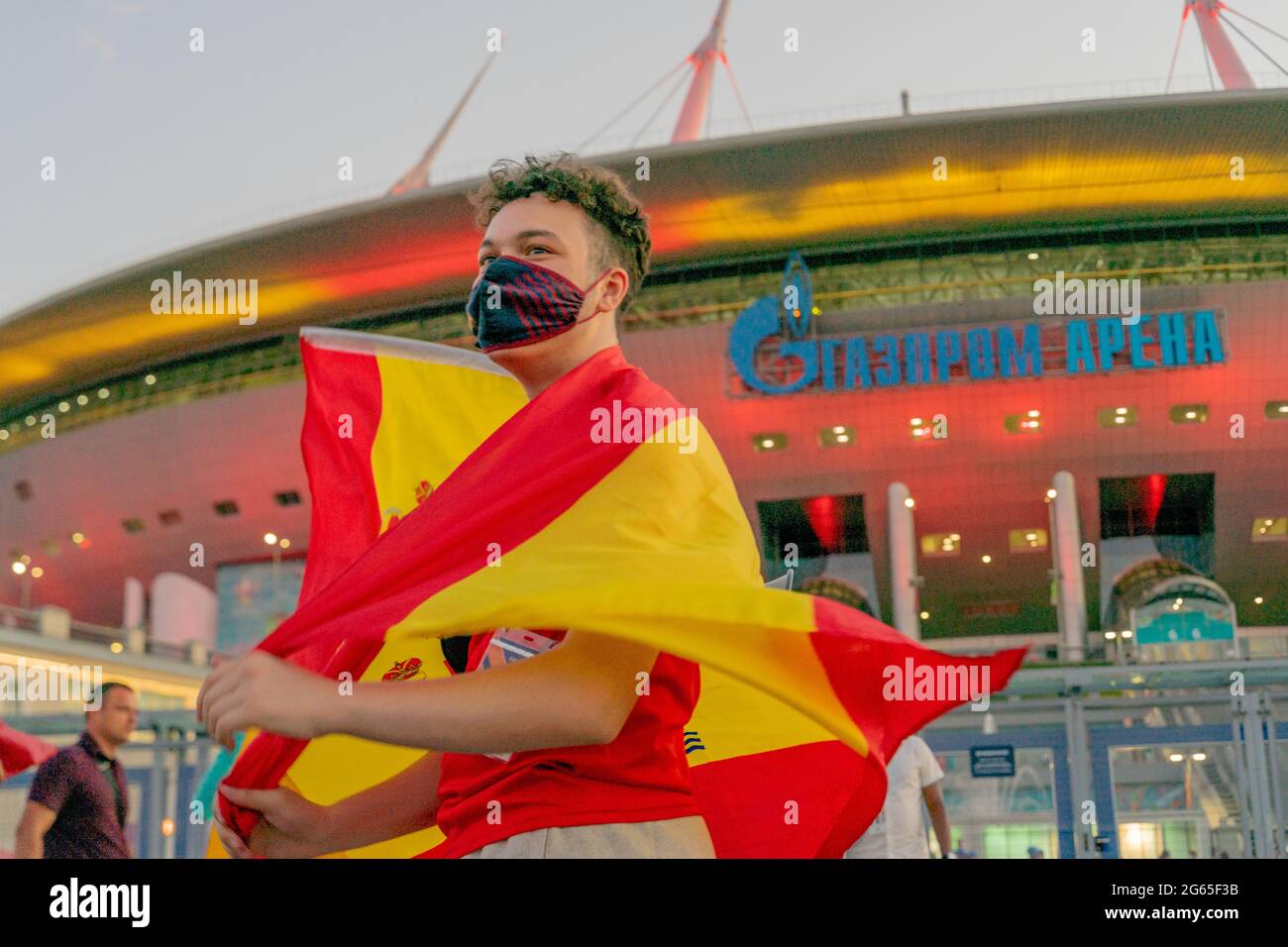 Fan de football espagnol caucasien de sexe masculin enveloppé dans un drapeau national, avec masque facial, célébrant la victoire du quart de finale du match, Saint-Pétersbourg, Russie Banque D'Images