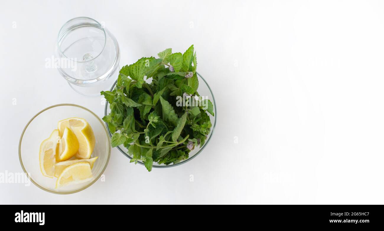 Trois bols en verre. Un bol avec des feuilles de menthe. Un bol avec des quartiers de citron et un verre d'eau potable. Vue de dessus Banque D'Images