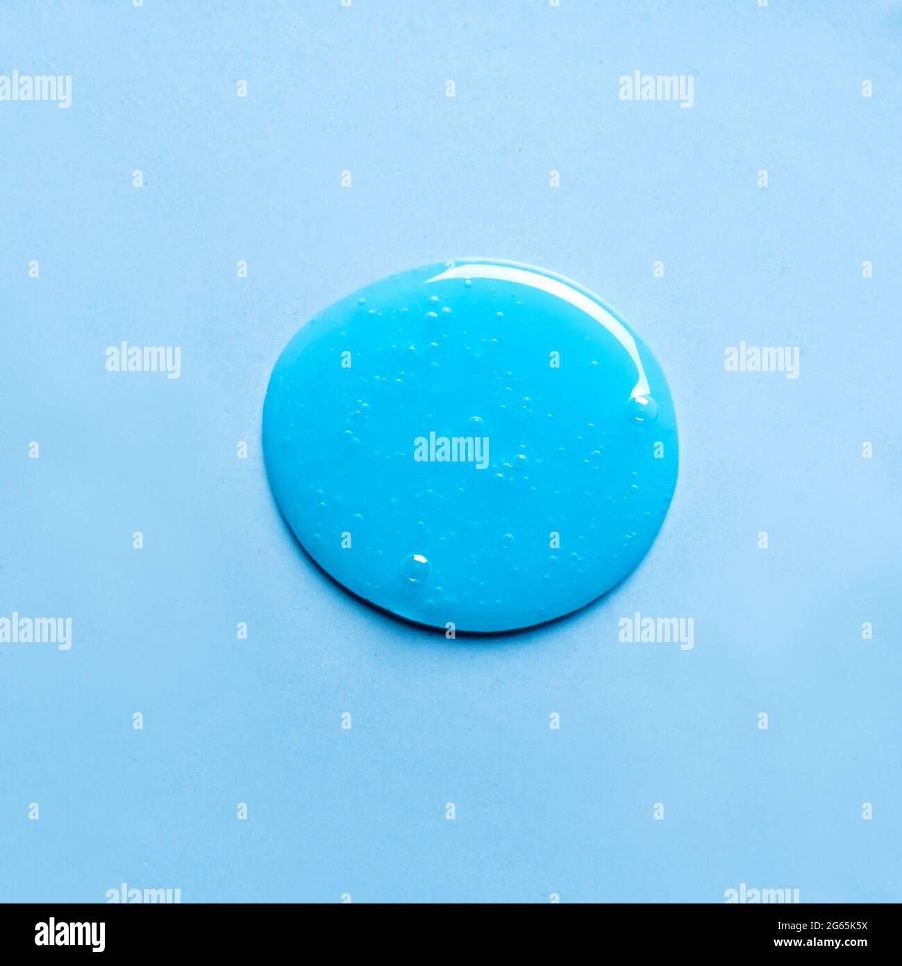 L'échantillon de shampooing bleu ou de gel douche tombe sur fond bleu. Produit cosmétique Blue Gel avec bulles. Banque D'Images