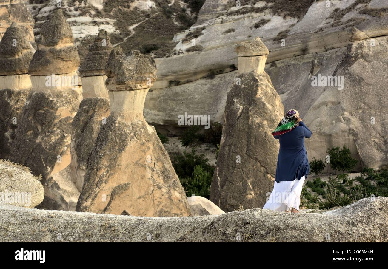 Un souvenir photo des cheminées de fées dans la vallée de Zelve point de repère du tourisme en Cappadoce femme musulmane prenant des photos d'une formation de roche en Turquie Banque D'Images