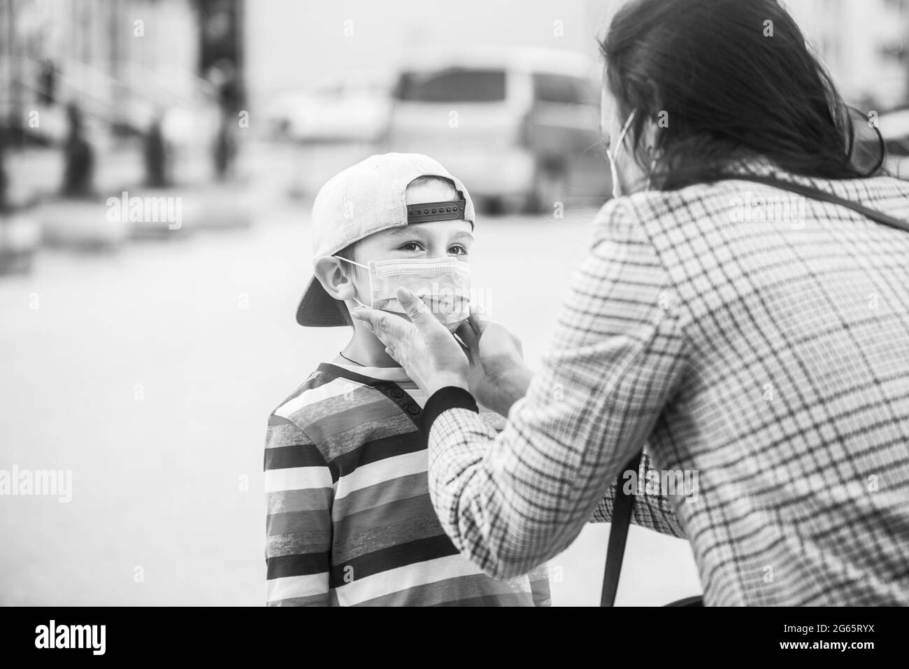 La mère, l'enfant porte un masque facial pendant le coronavirus, l'éclosion de grippe. Maman met un masque médical sur son fils. Enfant et mère dans un masque médical lors d'une promenade. Noir et Banque D'Images