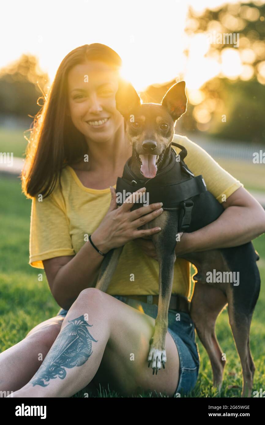 Belle femme assise et tenant son chien dans le parc Banque D'Images