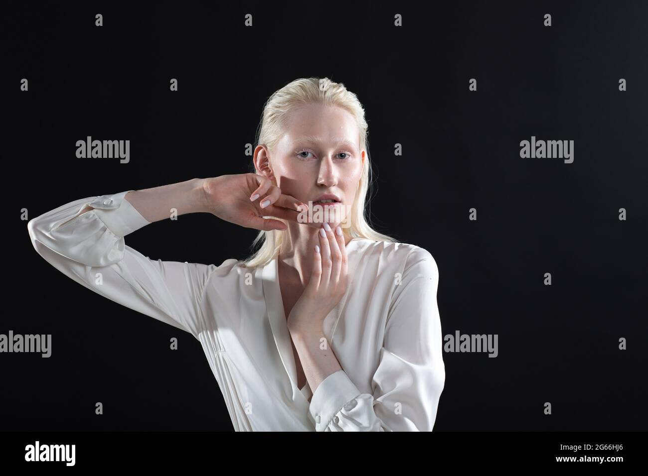 Jeune femme blonde albino faisant la gymnastique faciale automassage et des exercices rajeunissants sur fond noir. Banque D'Images