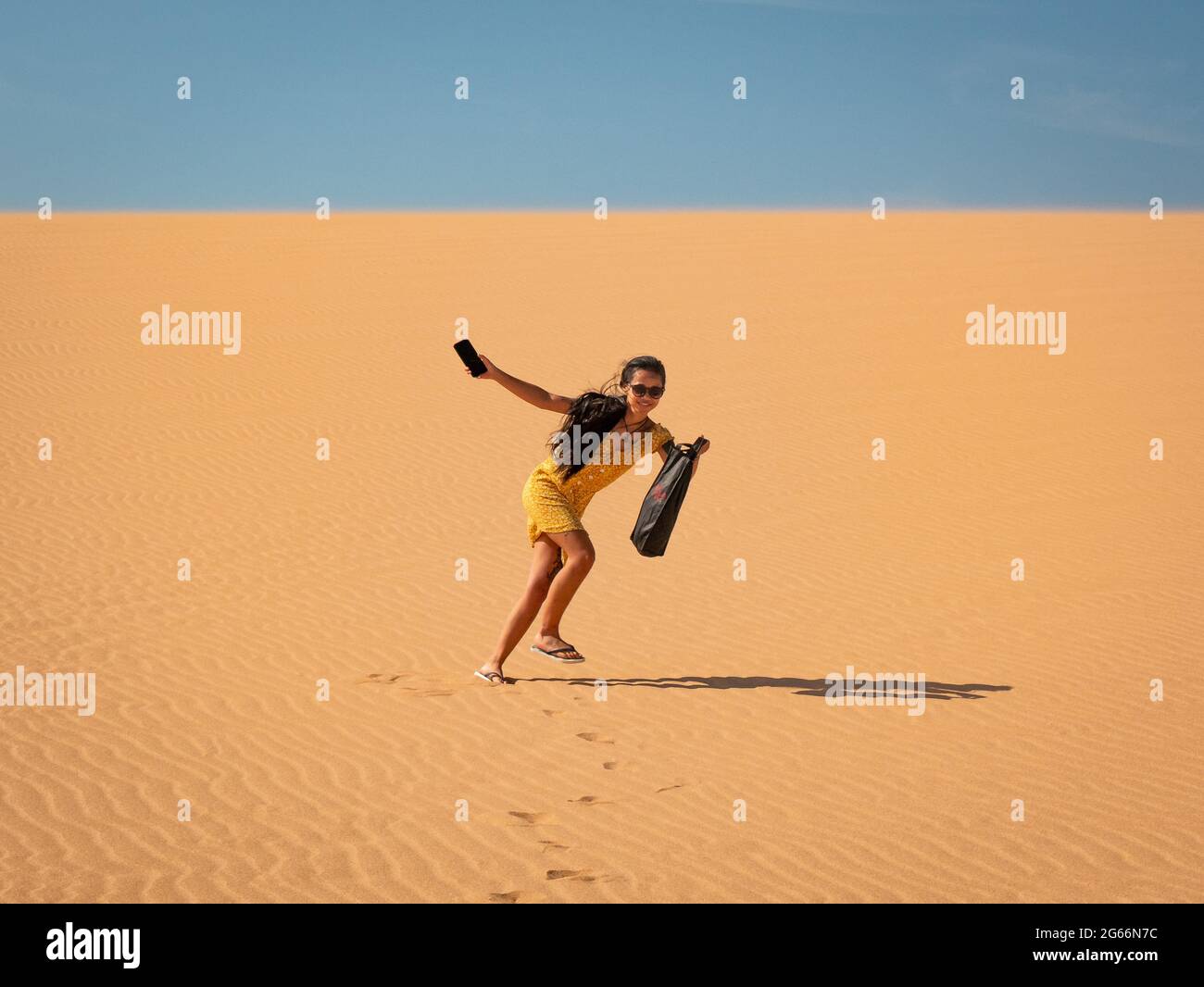 Une jeune femme asiatique attirante porte un sac à pied pour les dunes de Taroa Banque D'Images