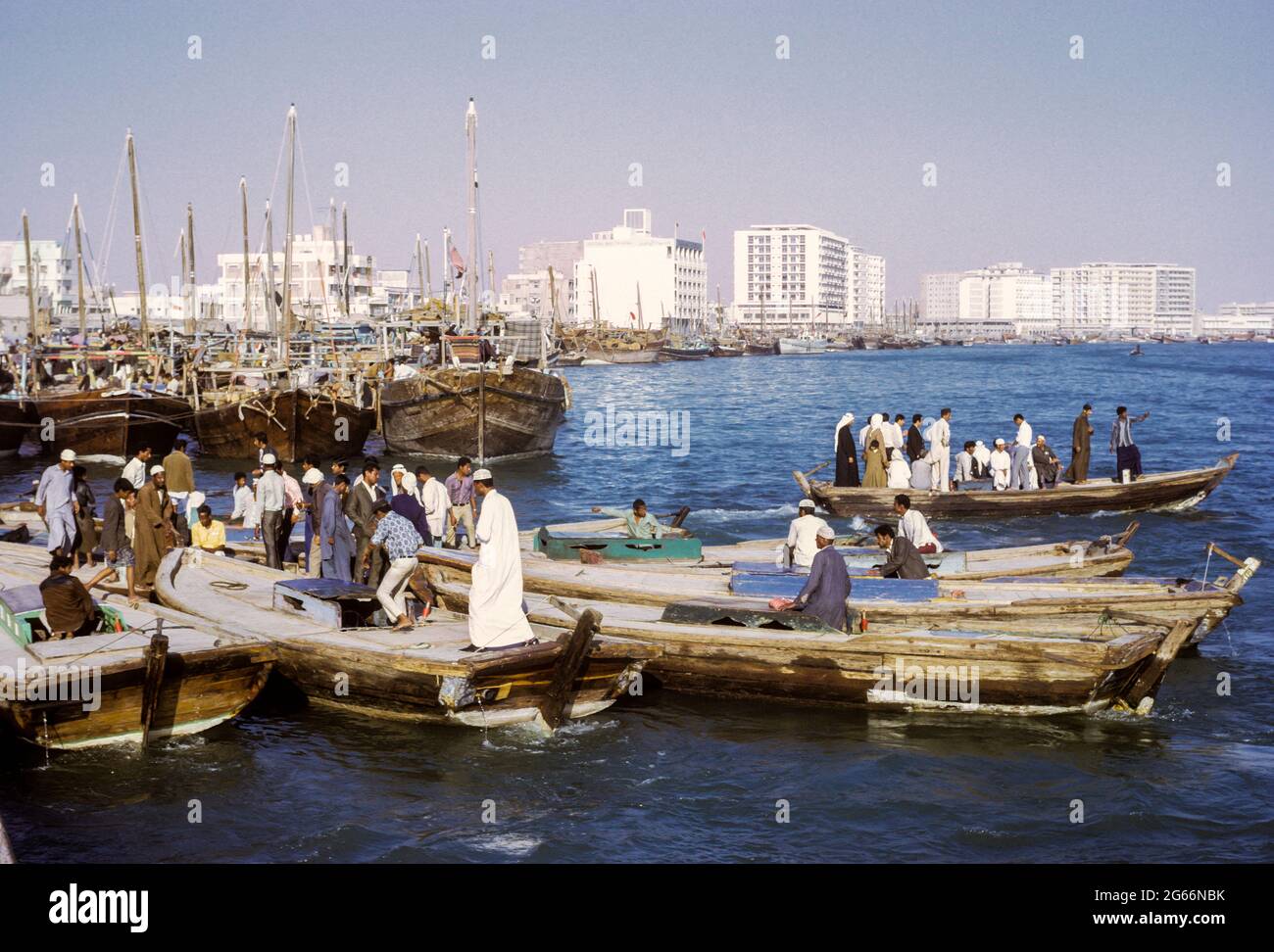 Dubai 1972, Émirats Arabes Unis. Abras (bateaux-taxis) traversant la crique. Banque nationale de Dubaï au centre; immeubles d'appartements et de bureaux en arrière-plan. Banque D'Images