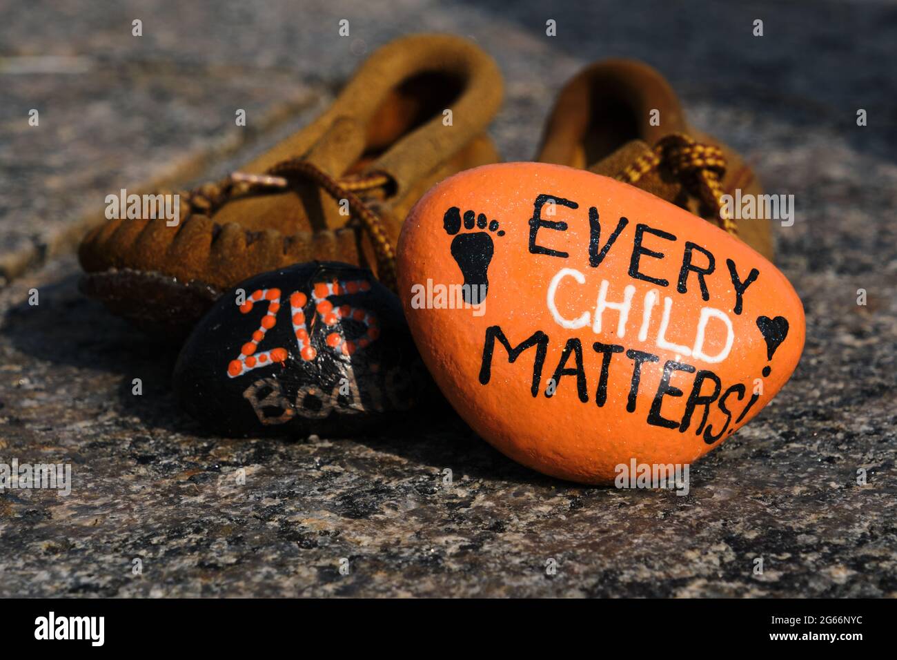 Mémorial aux enfants autochtones qui demeurent dans les pensionnats du Canada. Mocassin pour enfants et roche orange peinte en mémoire, Ottawa Banque D'Images