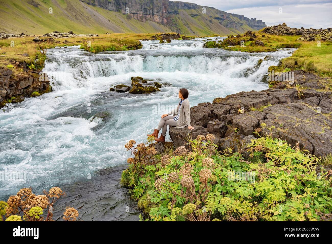 Femme assise près d'une cascade sur l'Islande. Fille touriste visite incroyable paysage de la nature islandaise Banque D'Images