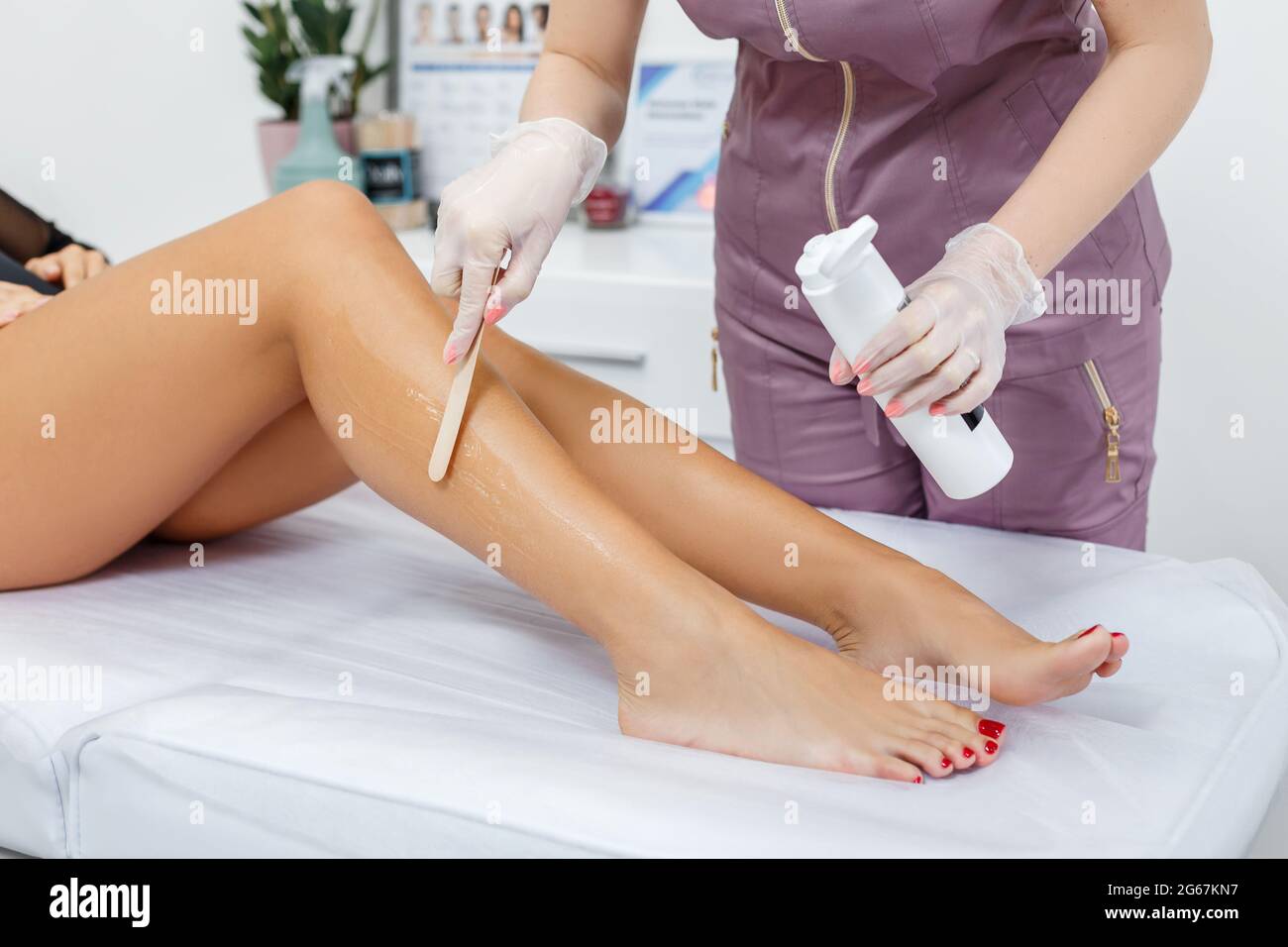 Un cosmétologue couvrant les jambes de la femme avec du gel anesthésique pendant l'épilation au laser. Épilation au laser sans douleur dans le salon de spa Banque D'Images