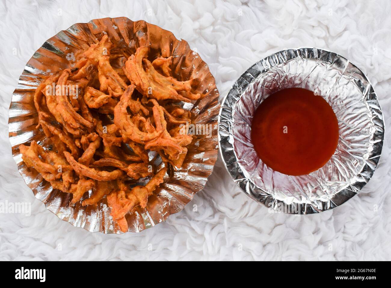 Délicieux en-cas indiens Pakoda d'oignon à base de farine de graminée et frite. Tea Time, des collations populaires faites maison en inde. Servi dans une assiette de papier et de tomates etc Banque D'Images